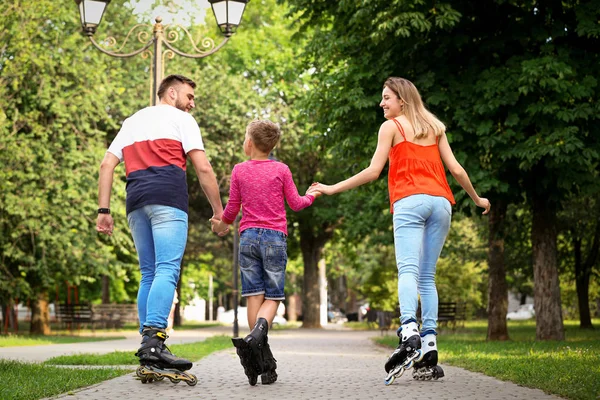 Patinação de rolo jovem família no parque, visão traseira — Fotografia de Stock