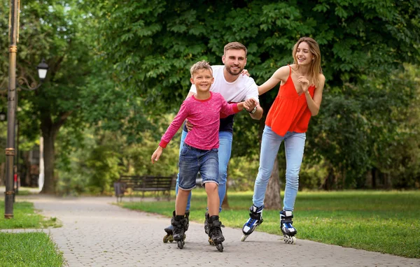 Giovane famiglia felice pattinaggio a rotelle nel parco estivo — Foto Stock