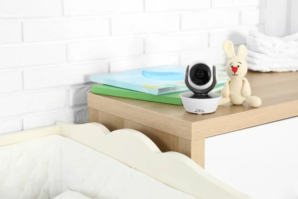 Baby camera met boeken en speelgoed op de commode bij wieg in de kamer, ruimte voor tekst. Video Nanny — Stockfoto