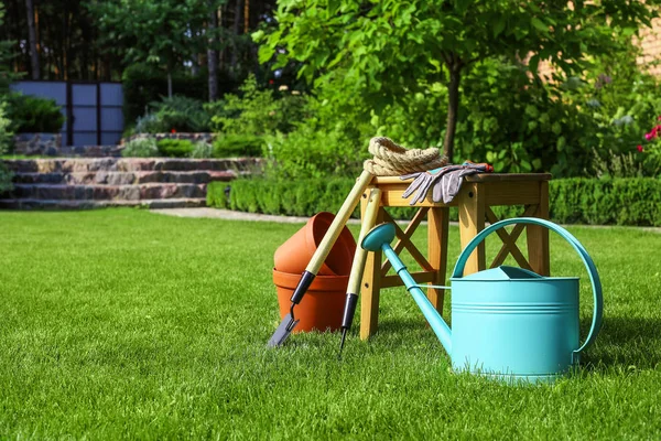 Set of gardening tools and stool on green grass — Stock Photo, Image