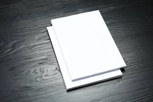 Stack of blank paper sheets for brochure on black wooden background. Mock up — Stock Photo, Image