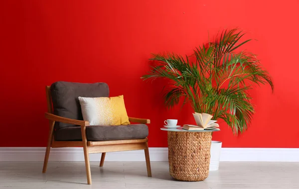 赤い壁の近くにモダンな家具やハウスプラントが備わるスタイリッシュな客室インテリア — ストック写真