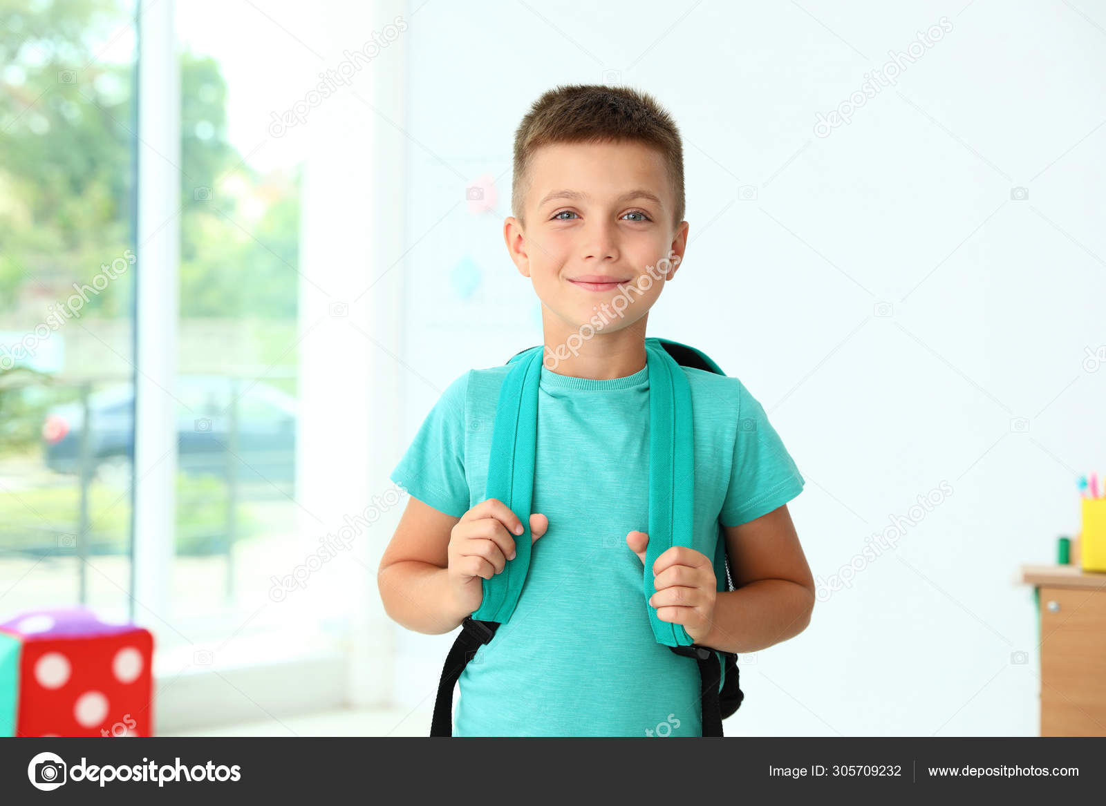 Cute little boy with backpack in classroom at school Stock Photo by