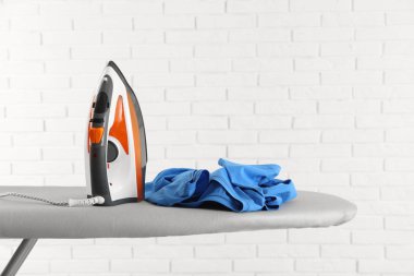 Tuğla duvara karşı gemide modern elektrikli demir ve temiz t-shirt. Metin için alan