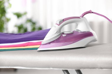 Modern elektrikli demir ve kapalı gemide temiz katlanmış giysiler