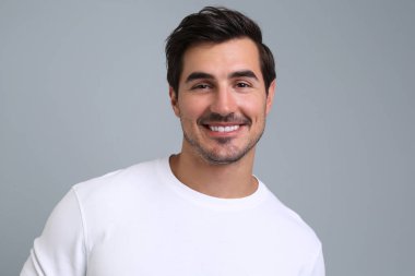 Gri arka plan üzerinde beyaz t-shirt yakışıklı genç adam Portresi
