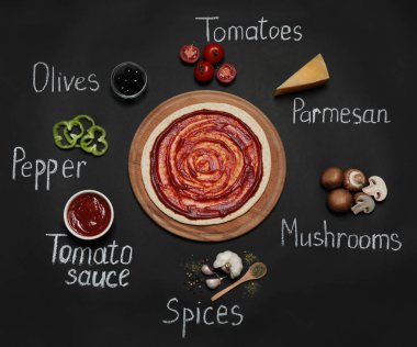 Pizza kabuk, malzemeler ve siyah arka plan üzerinde tebeşir yazılı ürünün isimleri, düz yatıyordu