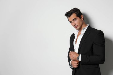 Hafif bej arka planda zarif takım elbiseli yakışıklı genç adam. Metin için alan