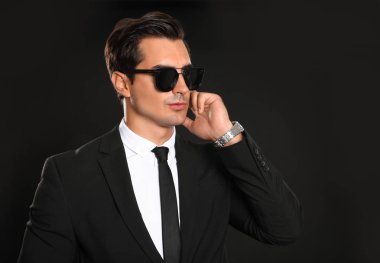 Koyu arka planda radyo kulaklık kullanarak üniformalı erkek güvenlik görevlisi