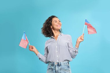mavi arka plan üzerinde Amerikan bayrakları ile mutlu genç kadın