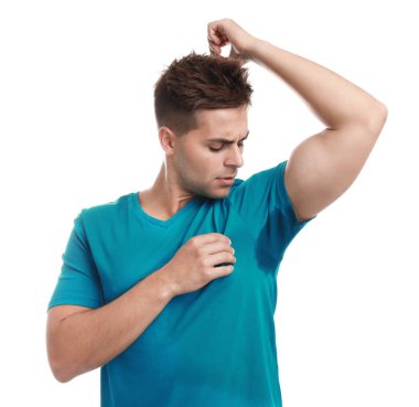 Beyaz arka plana karşı giysilerinde ter lekesi olan genç bir adam. Deodorant kullanma