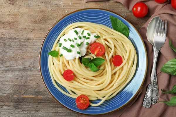 Leckere Spaghetti mit saurer Sahne auf Holztisch serviert, flache Lage — Stockfoto