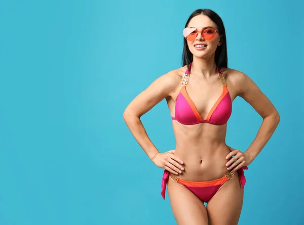 Hermosa mujer joven en bikini elegante con gafas de sol sobre fondo azul claro. Espacio para texto —  Fotos de Stock