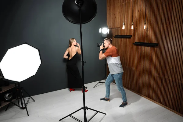 Fotógrafo profesional tomando fotos de una mujer joven en un estudio moderno — Foto de Stock