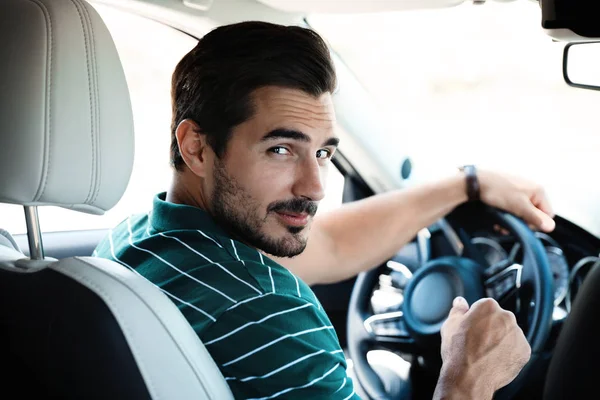 Attraente giovane uomo guida auto di lusso, vista dal sedile posteriore — Foto Stock