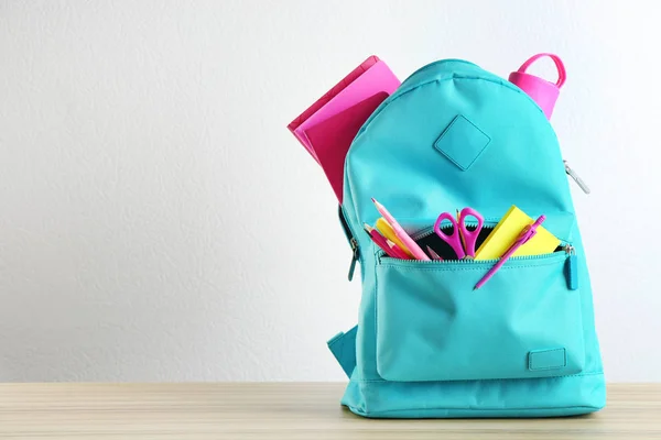 Mochila brilhante com diferentes artigos de papelaria escolar em mesa de madeira contra fundo branco. Espaço para texto — Fotografia de Stock