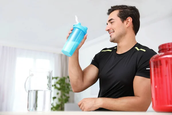 Young athletic man with protein shake at home, space for text — Stock Photo, Image
