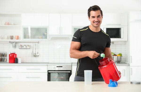 Hombre atlético joven preparando batido de proteínas en la cocina, espacio para el texto —  Fotos de Stock