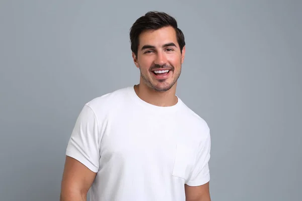 Portrait de beau jeune homme en t-shirt blanc sur fond gris — Photo