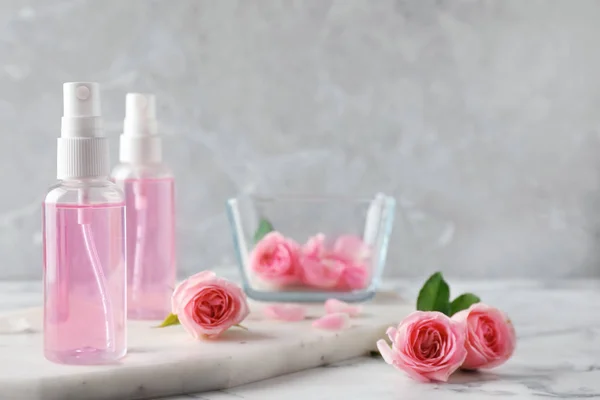 Rózsa illóolaj-és virágpalackok márvány asztalon, hely a szöveg — Stock Fotó