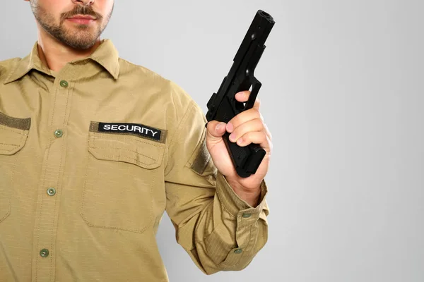 Guardia de seguridad masculino en uniforme con pistola sobre fondo gris, primer plano. Espacio para texto — Foto de Stock