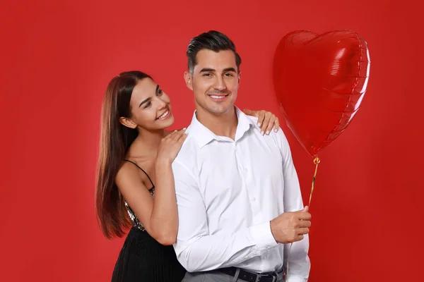 Vackert par med hjärtformad ballong på röd bakgrund — Stockfoto