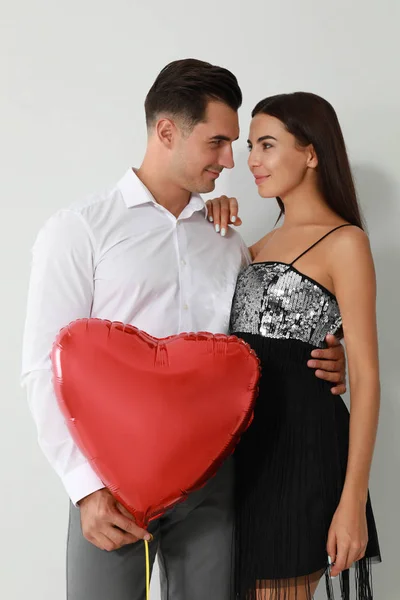 Όμορφο ζευγάρι με το σχήμα της καρδιάς μπαλόνι σε φως φόντο — Φωτογραφία Αρχείου