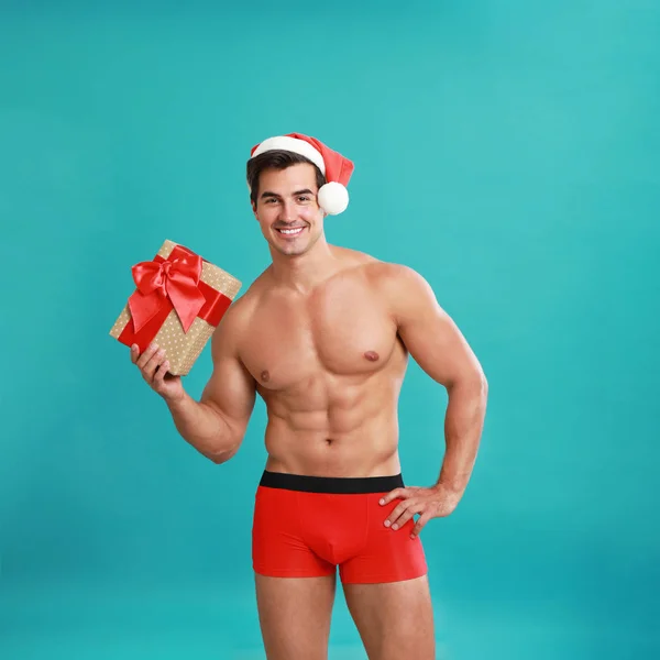 Sexy Santa Claus sin camisa con regalo sobre fondo azul —  Fotos de Stock