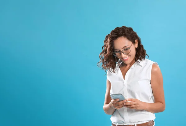 Mujer joven feliz usando teléfono inteligente sobre fondo azul. Espacio para texto — Foto de Stock