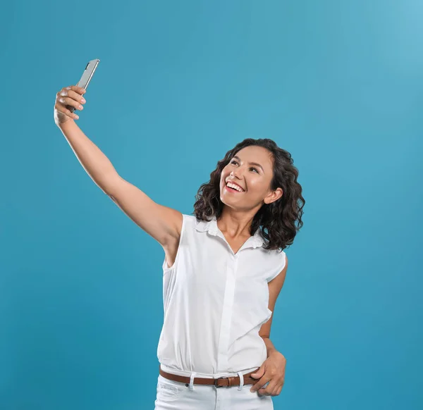 Jovem feliz tomando selfie no fundo azul — Fotografia de Stock