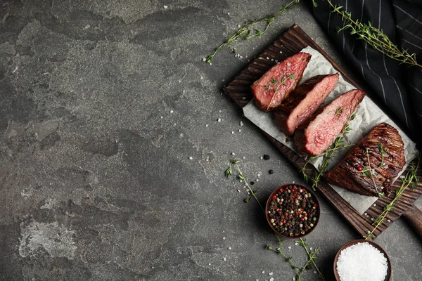 Composizione posata piatta con fette di carne alla griglia su tavola grigia. Spazio per testo — Foto Stock