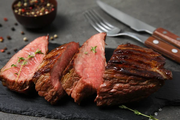 Bord met schijfjes gegrild vlees op grijze tafel, close-up — Stockfoto