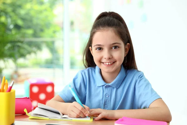 教室の机で宿題をしている小さな女の子。学校文房具 — ストック写真