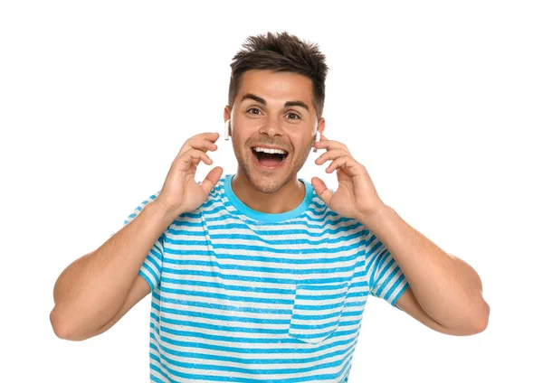 Happy young man listening to music through wireless earphones on white background — Stock Photo, Image