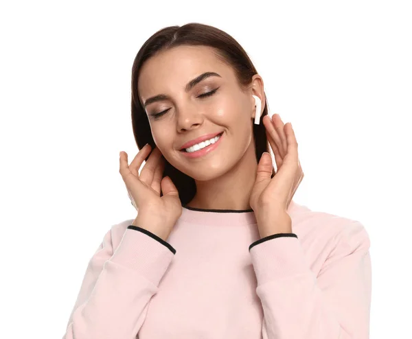 Mujer joven y feliz escuchando música a través de auriculares inalámbricos sobre fondo blanco — Foto de Stock