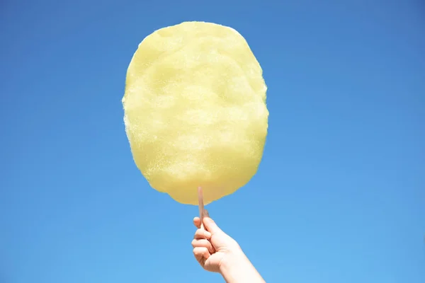 Mulher segurando algodão branco doce contra o céu azul — Fotografia de Stock