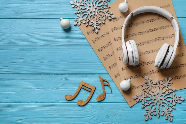 Flache Liegekomposition mit Weihnachtsdekoration, Kopfhörern und Notenblättern auf blauem Holztisch, Platz für Text — Stockfoto