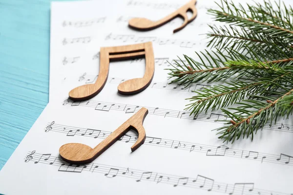 Χριστουγεννιάτικο δέντρο κλαδί, νότες και φύλλα μουσικής σε μπλε ξύλινο τραπέζι — Φωτογραφία Αρχείου