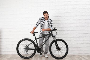 Kapalı beyaz tuğla duvar yakınında modern bisiklet ile Yakışıklı genç adam