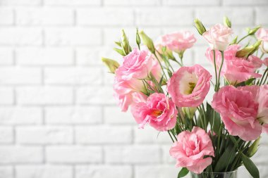 Beyaz tuğla duvara yakın Eustoma çiçekler, metin için alan