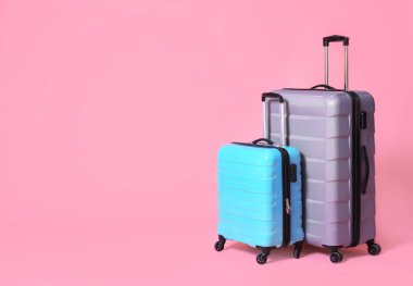 Açık pembe arka planda modern bavullar. Metin için alan