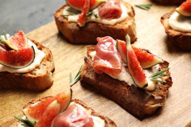 Krem peynir, prosciutto ve incir ile Bruschettas ahşap tahta, closeup servis