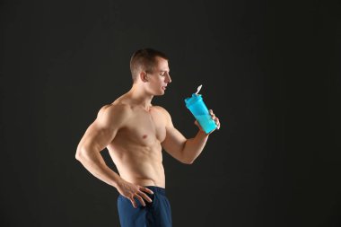 Siyah arka plan üzerinde protein sallamak ile Atletik genç adam