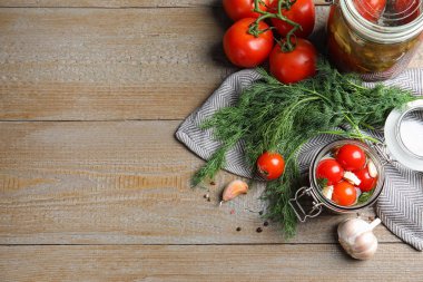 Ahşap masa üzerinde cam kavanozlarda salamura domates ile Düz yatıyordu kompozisyon, metin için alan