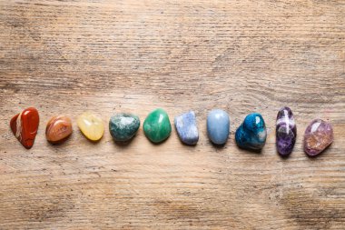 Flat lay composition with different gemstones on wooden table clipart