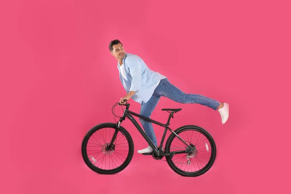 Красивий молодий чоловік з сучасним велосипедом на рожевому фоні — стокове фото