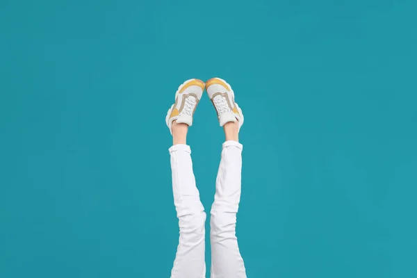 Woman in stylish sport shoes on light blue background