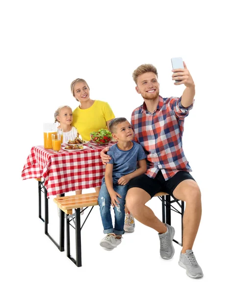 Щаслива сім'я приймає селфі за столом для пікніка на білому тлі — стокове фото