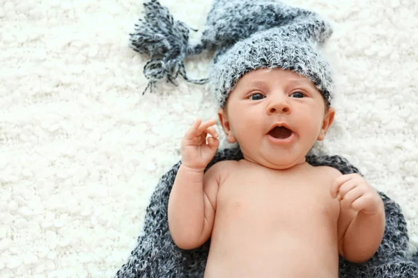 Bebê bonito em chapéu cinza e xadrez deitado em cobertor macio, vista superior. Espaço para texto — Fotografia de Stock