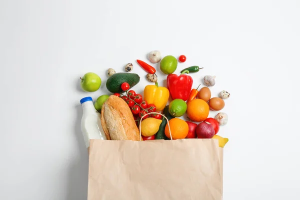 Bolsa de papel con diferentes comestibles sobre fondo blanco, vista superior —  Fotos de Stock